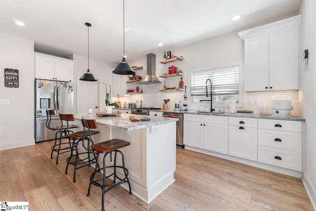 kitchen featuring a sink, backsplash, ventilation hood, light wood-style floors, and appliances with stainless steel finishes