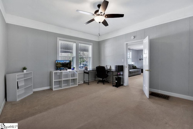 office space featuring baseboards, a ceiling fan, visible vents, and light carpet