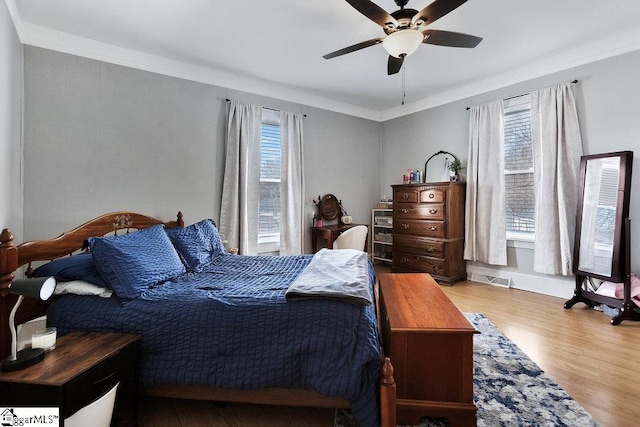 bedroom featuring a ceiling fan, wood finished floors, visible vents, and ornamental molding