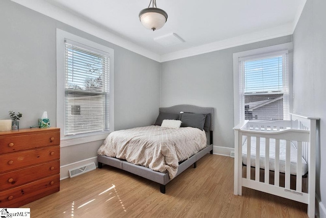 bedroom featuring crown molding, wood finished floors, visible vents, and baseboards