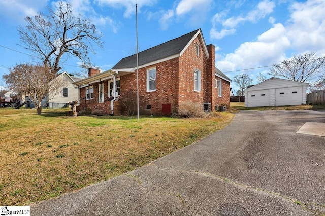 view of side of home with a detached garage, a lawn, brick siding, and a chimney