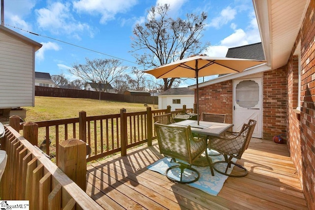 deck with a fenced backyard, outdoor dining area, and a yard