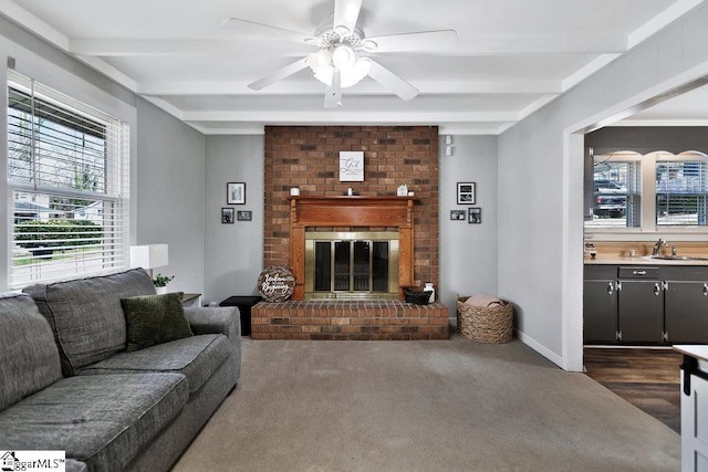 living room featuring beamed ceiling, a fireplace, baseboards, and ceiling fan