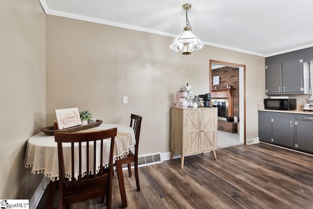 dining area with visible vents, baseboards, dark wood finished floors, a fireplace, and ornamental molding