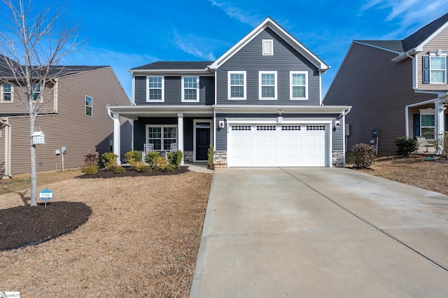 traditional home featuring a porch, concrete driveway, an attached garage, and stone siding