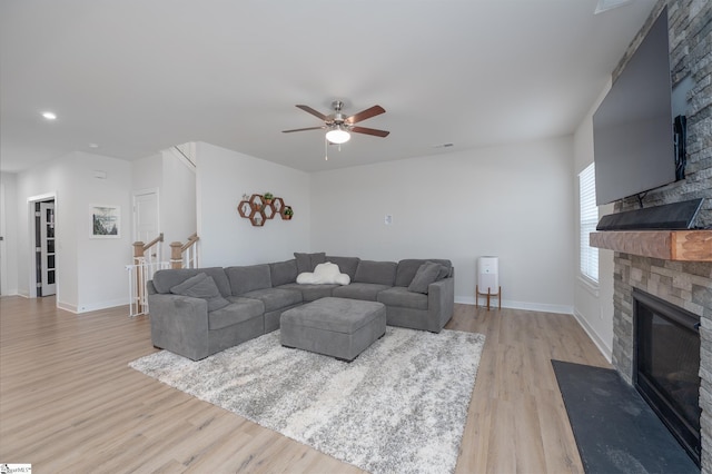 living area featuring wood finished floors, a fireplace, baseboards, and ceiling fan