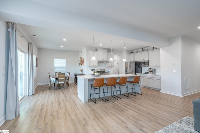 kitchen with visible vents, light wood-style flooring, stainless steel appliances, white cabinets, and under cabinet range hood