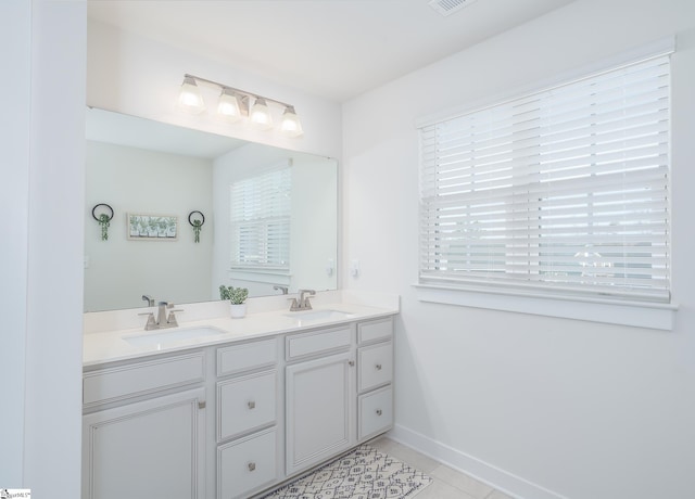 bathroom featuring double vanity, tile patterned flooring, baseboards, and a sink