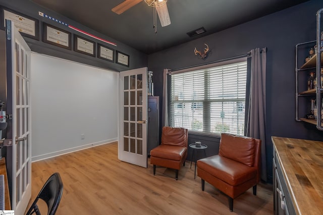 living area with a ceiling fan, wood finished floors, french doors, and visible vents