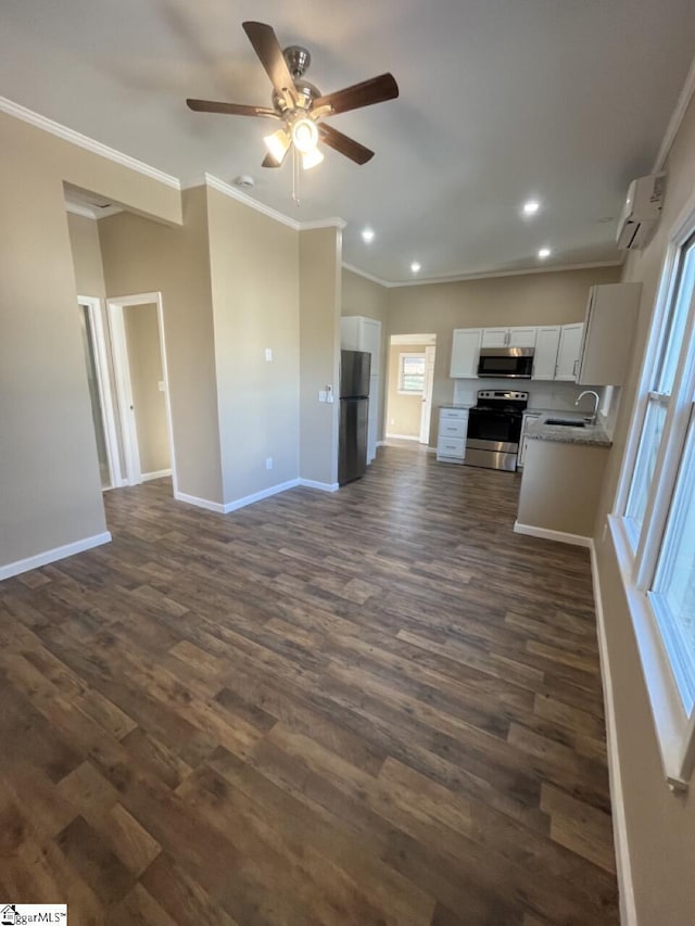 unfurnished living room featuring ornamental molding, a ceiling fan, a sink, baseboards, and dark wood-style flooring