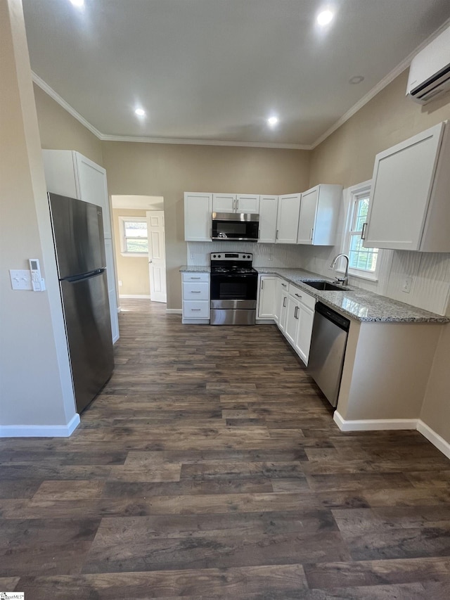 kitchen featuring light stone counters, decorative backsplash, appliances with stainless steel finishes, a wall mounted AC, and a sink