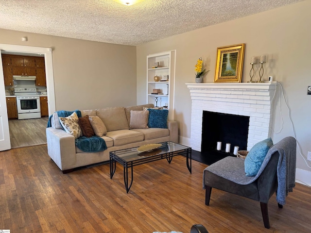 living room featuring built in features, a textured ceiling, dark wood-style floors, and a fireplace