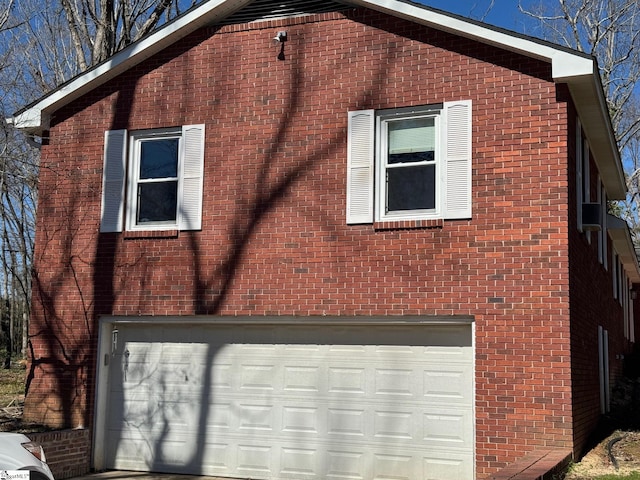 view of home's exterior with a garage, brick siding, and driveway