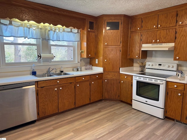 kitchen with white range with electric cooktop, under cabinet range hood, dishwasher, brown cabinetry, and a sink