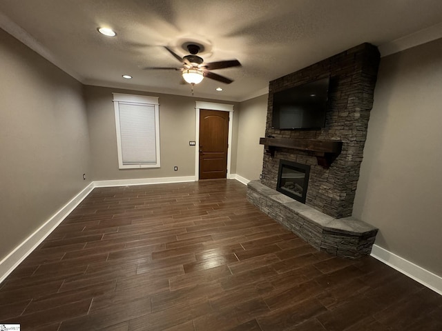 unfurnished living room featuring wood finish floors, baseboards, a stone fireplace, and a ceiling fan