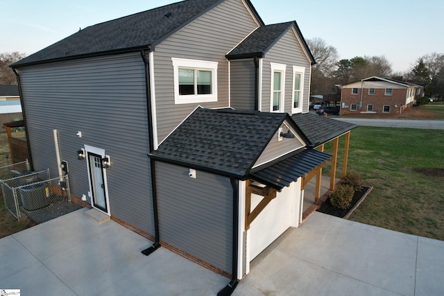 view of property exterior with a patio area, a yard, fence, and a shingled roof