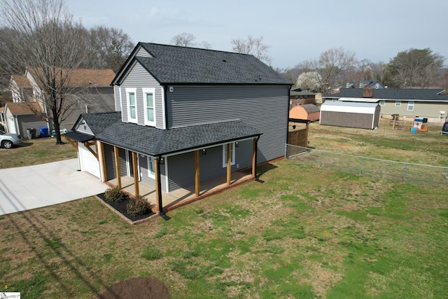 back of house with a lawn, driveway, roof with shingles, and fence