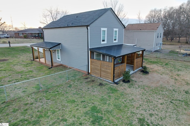 back of house featuring a lawn and fence