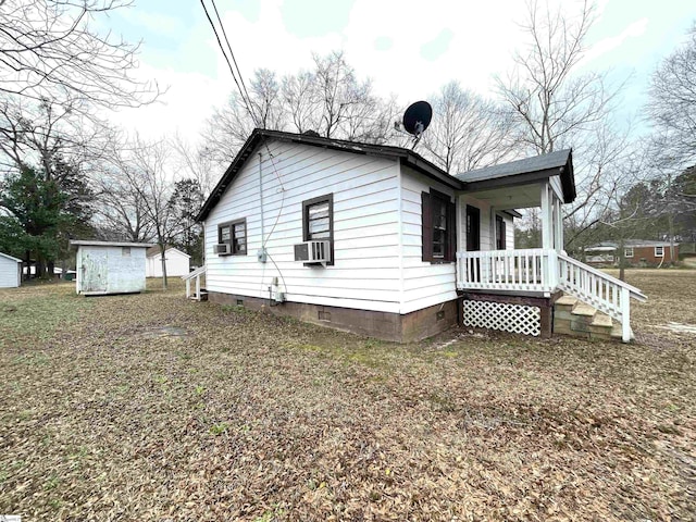 view of side of home with crawl space, an outbuilding, and covered porch