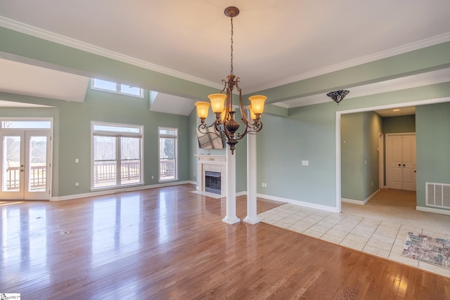 interior space with baseboards, visible vents, a tiled fireplace, a notable chandelier, and light wood-type flooring