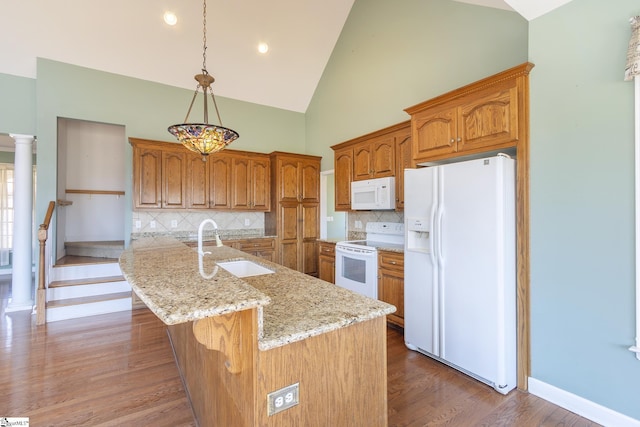 kitchen with white appliances, light stone counters, wood finished floors, a sink, and brown cabinets