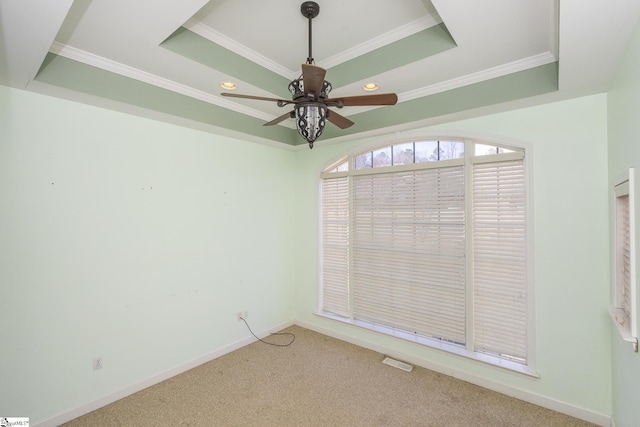 empty room featuring baseboards, a raised ceiling, light colored carpet, and ceiling fan