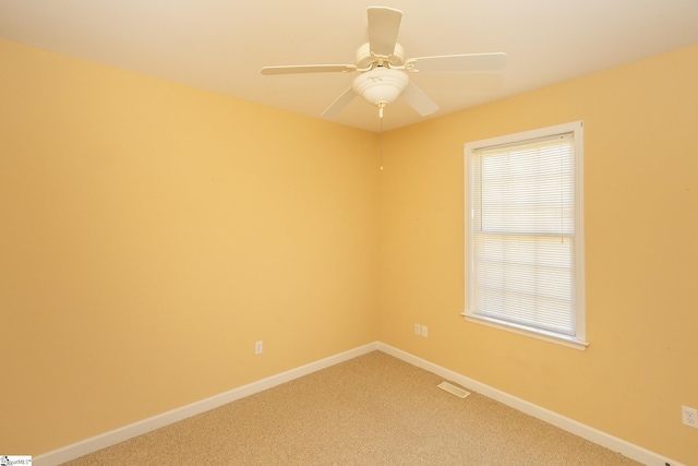 empty room with visible vents, baseboards, light colored carpet, and a ceiling fan