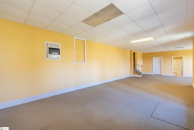 carpeted spare room with baseboards, a paneled ceiling, and stairs