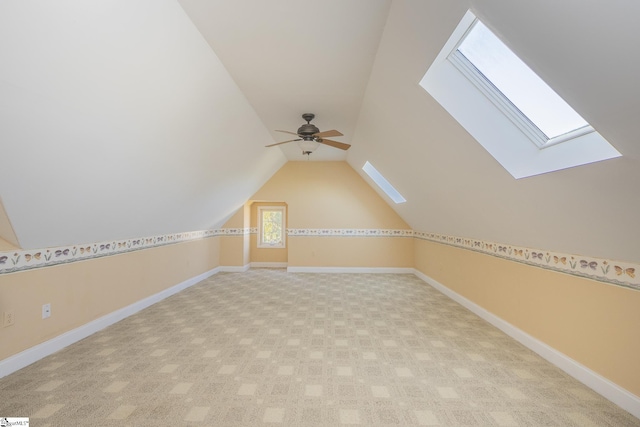 bonus room featuring vaulted ceiling with skylight, baseboards, and ceiling fan