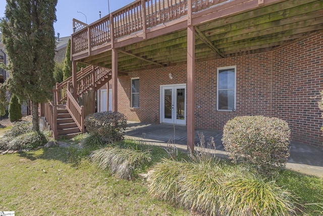 rear view of property featuring a deck, stairway, french doors, and brick siding