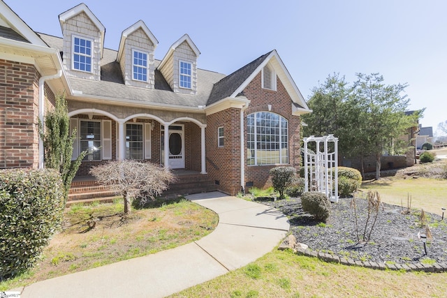 view of front of property featuring covered porch, brick siding, and a shingled roof