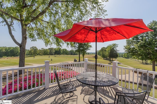 wooden terrace featuring outdoor dining space, view of golf course, and a lawn