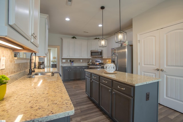 kitchen featuring visible vents, a kitchen island, dark wood finished floors, appliances with stainless steel finishes, and a sink