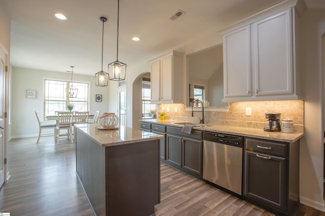 kitchen with visible vents, arched walkways, a sink, stainless steel dishwasher, and tasteful backsplash