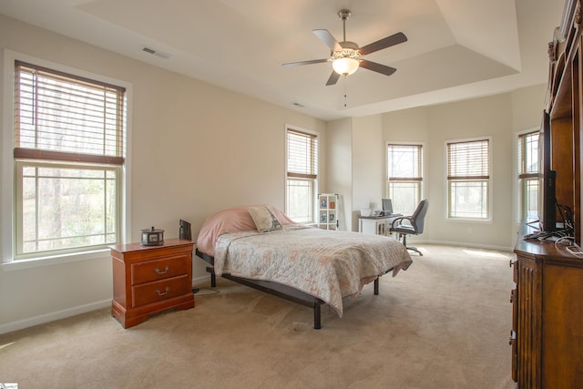 bedroom featuring a tray ceiling, light colored carpet, visible vents, and baseboards