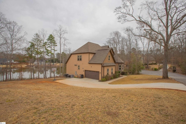 rear view of house with driveway, a yard, a shingled roof, a water view, and a garage