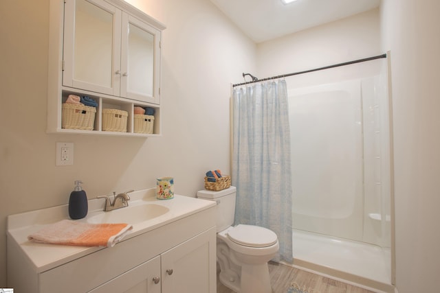 bathroom featuring vanity, a shower stall, toilet, and wood finished floors