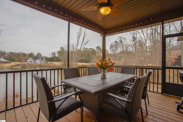 wooden deck with outdoor dining space, a ceiling fan, and a water view