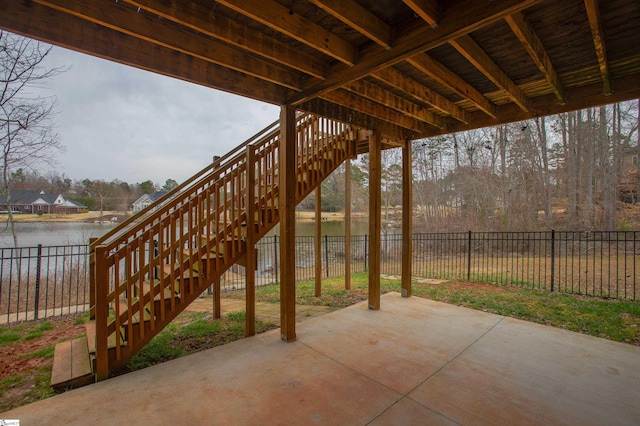 view of patio / terrace featuring stairs, a fenced backyard, and a water view