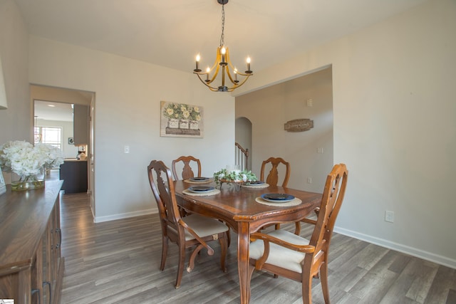 dining area with baseboards, arched walkways, an inviting chandelier, and wood finished floors