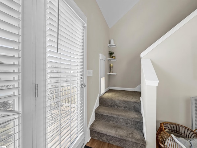 staircase with baseboards and lofted ceiling