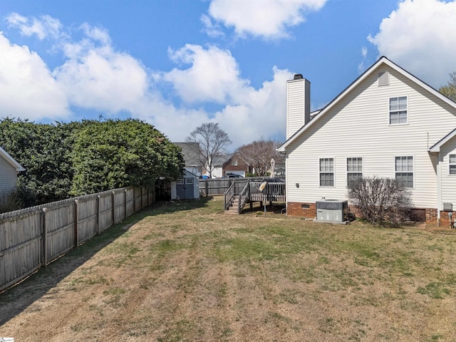 view of yard featuring an outbuilding, a deck, a fenced backyard, a shed, and cooling unit