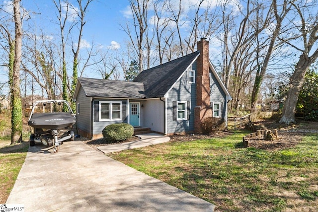 view of front of home with concrete driveway, a chimney, and a shingled roof