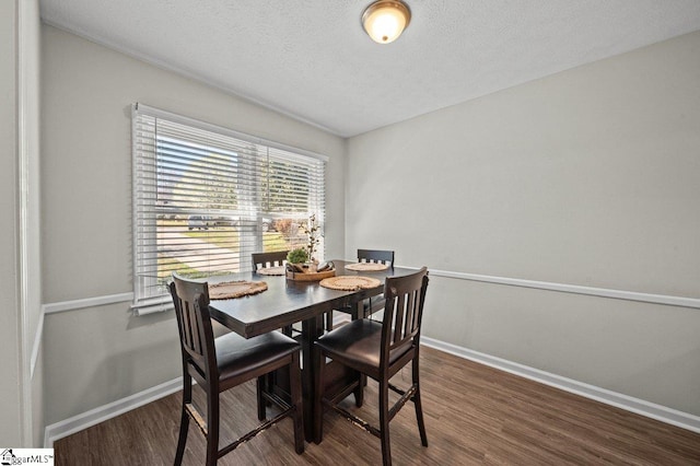 dining area with baseboards, a textured ceiling, and wood finished floors
