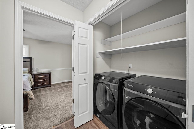 laundry room featuring carpet, wood finished floors, laundry area, a textured ceiling, and washer and clothes dryer