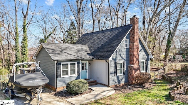 view of front of property featuring crawl space, roof with shingles, a chimney, and fence