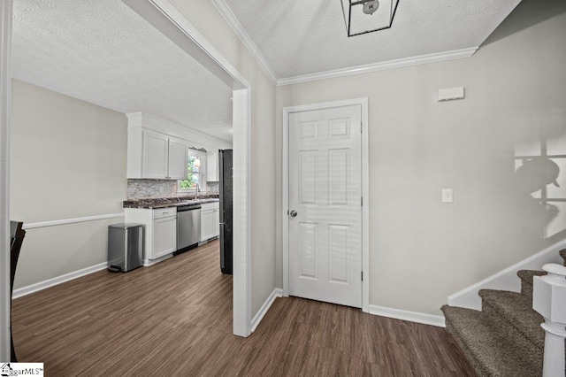interior space with dark wood-type flooring, a sink, backsplash, stainless steel dishwasher, and white cabinets
