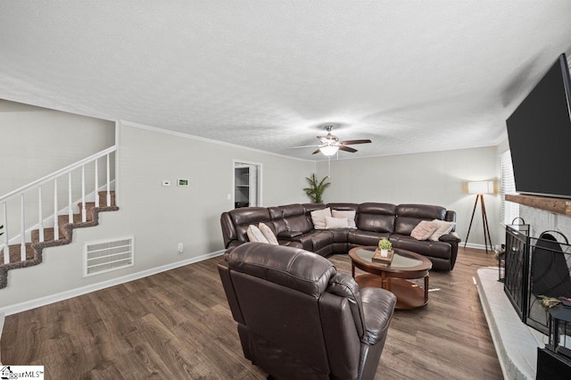 living room featuring visible vents, a textured ceiling, wood finished floors, ceiling fan, and stairs