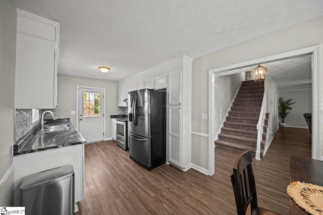 kitchen with dark wood-type flooring, a sink, dark stone counters, appliances with stainless steel finishes, and white cabinets