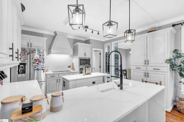 kitchen with stainless steel appliances, ornamental molding, a center island, and custom range hood